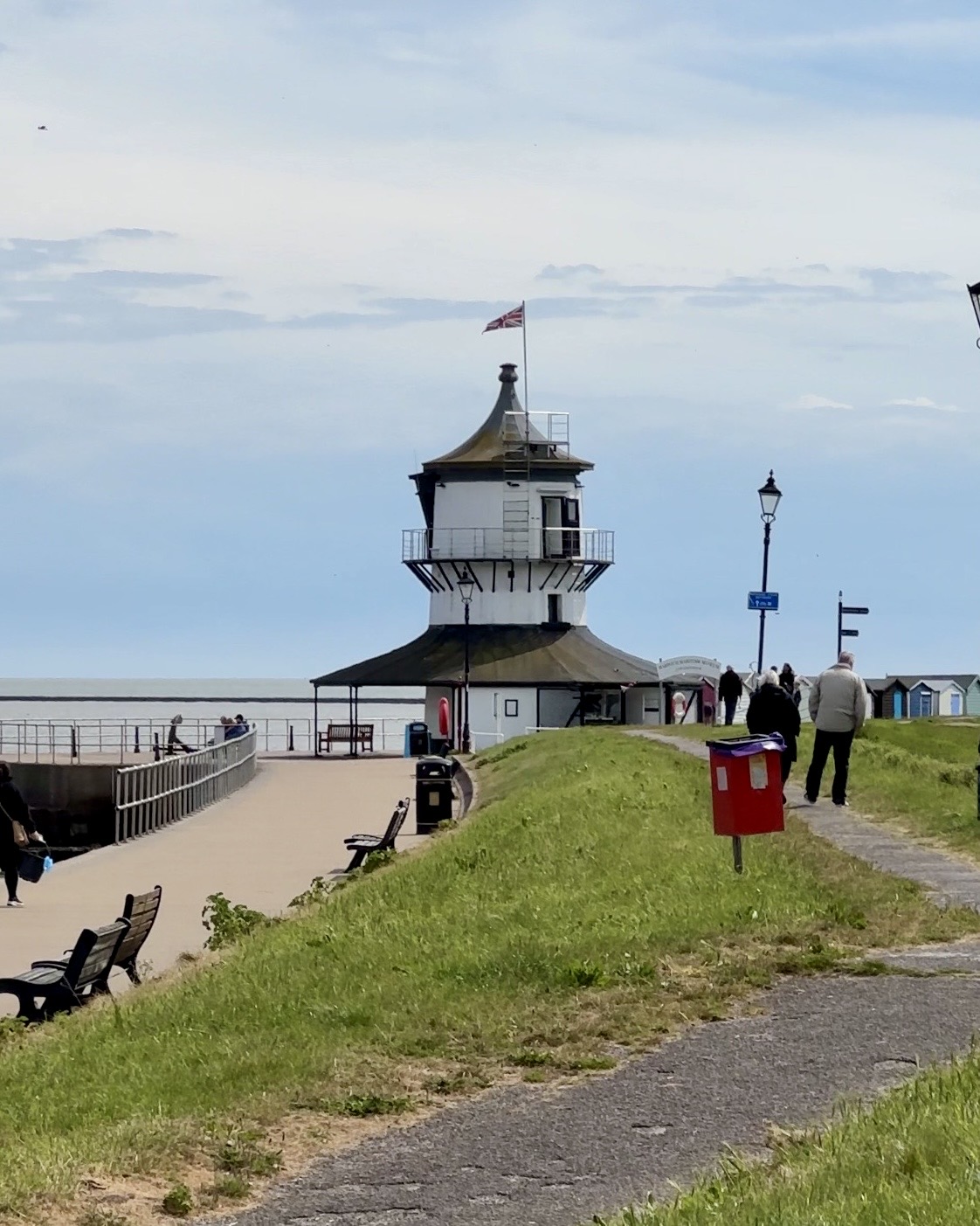 Harwich's low lighthouse, with a path to it in the foreground on the left, and a grassy field.