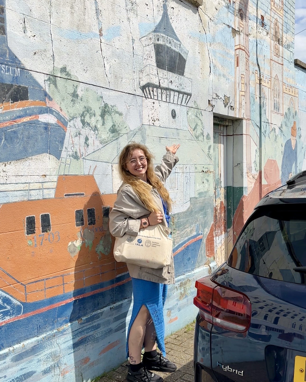 Annie next to a mural with a lighthouse on it.