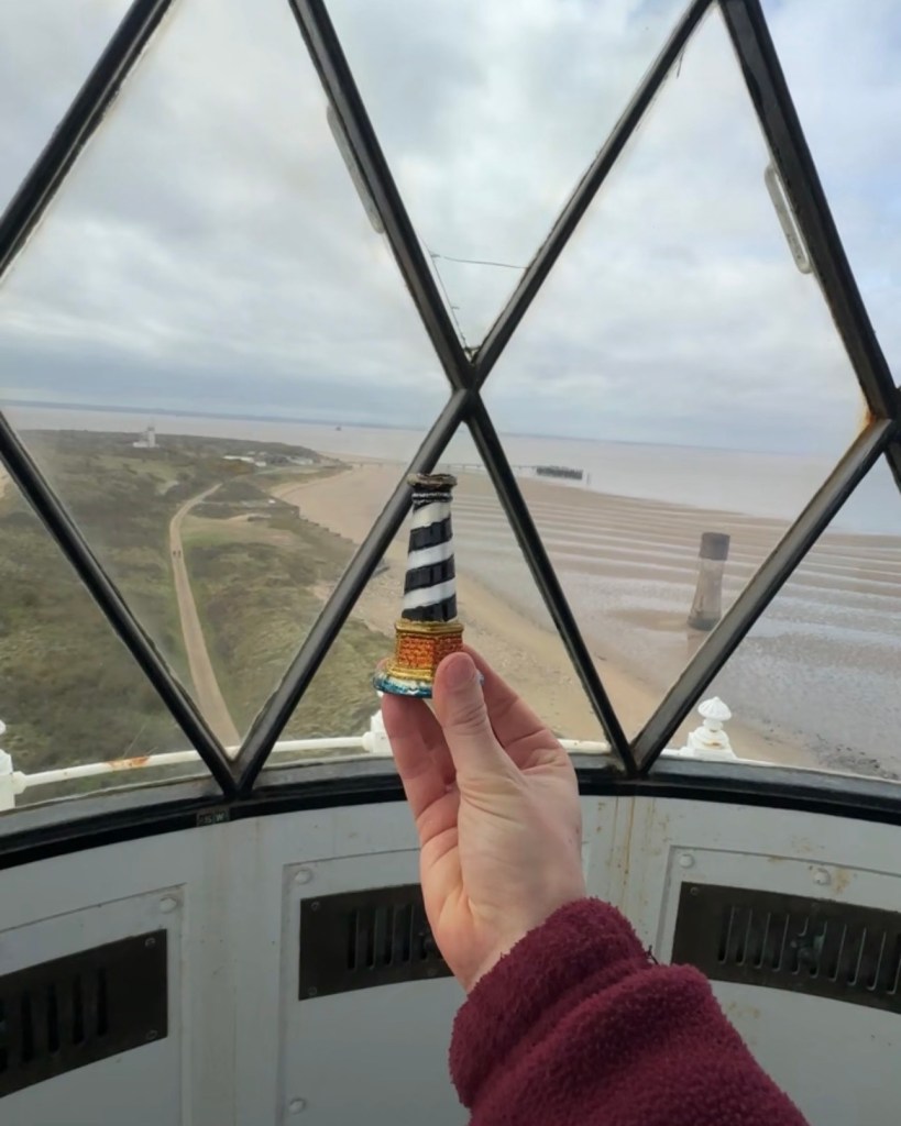 A small lighthouse being held up in the High Lighthouse's lantern room.