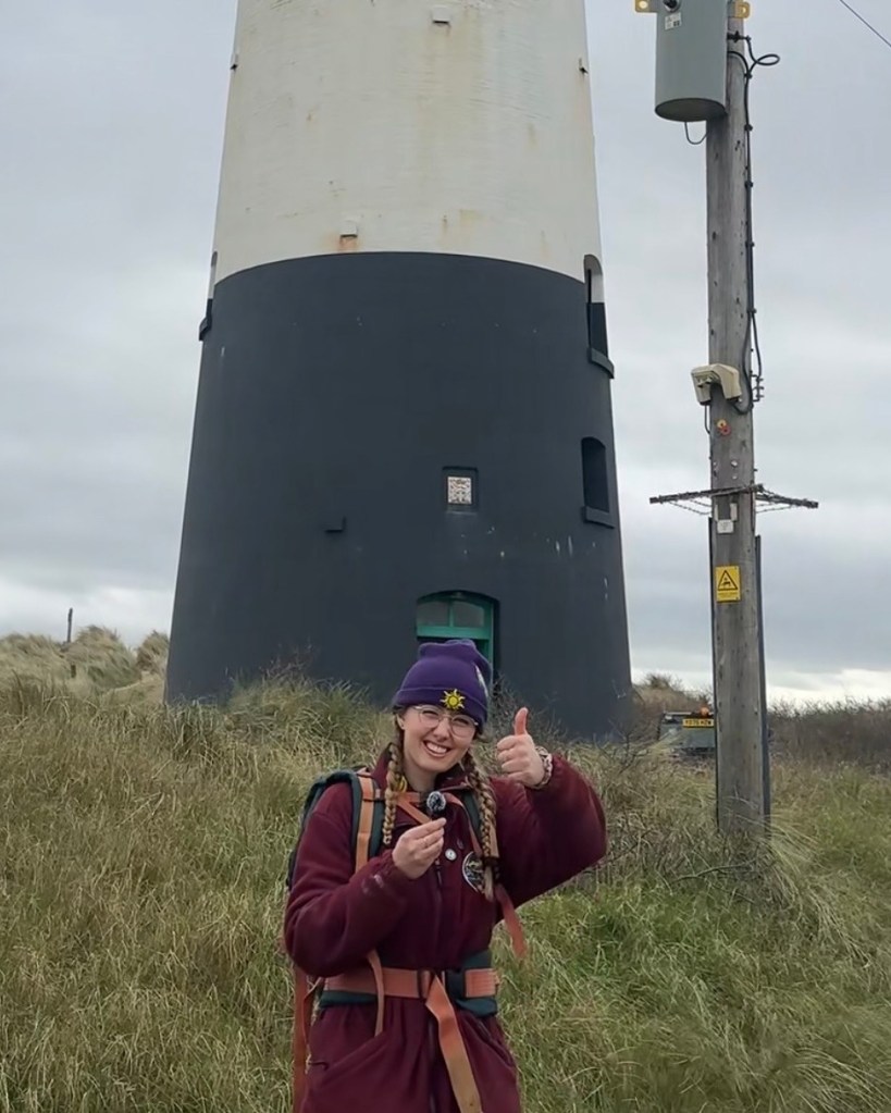 Annie outside of Spurn High Lighthouse, giving a thumbs up and a smile to the camera.